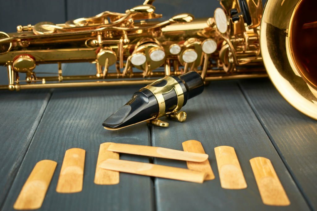 saxophone mouthpiece with metal clamp and gold adjustment hardware, with replacement reeds and instrument